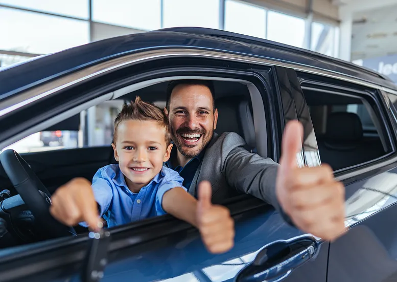 Mężczyzna z dzieckiem w samochodzie pokazujący kciuki w górę
